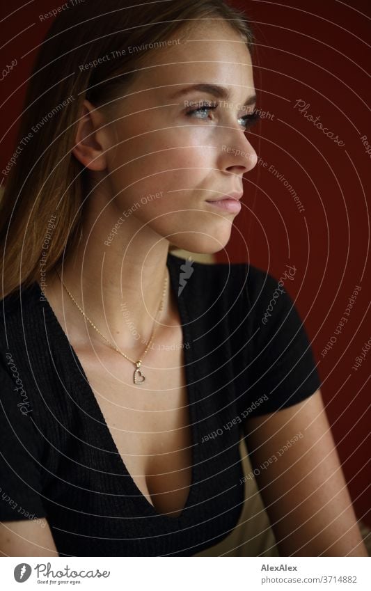 Lateral portrait of a young woman in front of a red wall Athletic Feminine empathy Emotions emotionally Central perspective Shallow depth of field