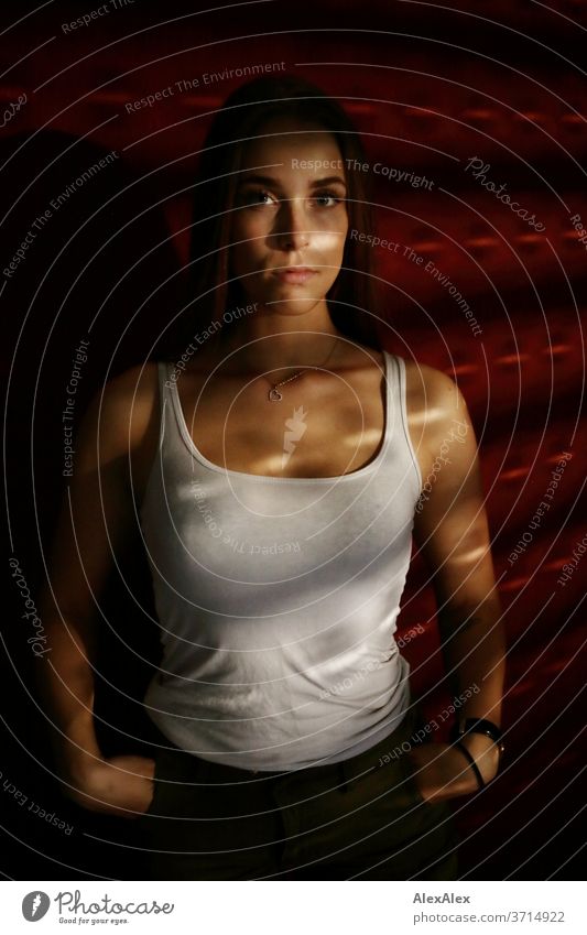 Portrait of a young woman in light stripes of blinds in front of red wall Venetian blinds Light and shadow Shadow Athletic Feminine empathy Emotions emotionally