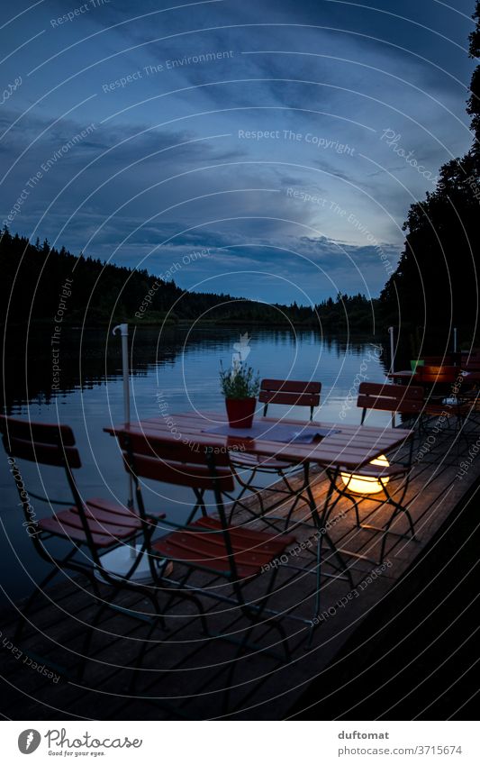 Table for four at the lake in the evening mood Lake Beer garden Idyll reflection Water Nature Reflection feed sb./sth. Blue Calm Sky Clouds Sunset Evening out