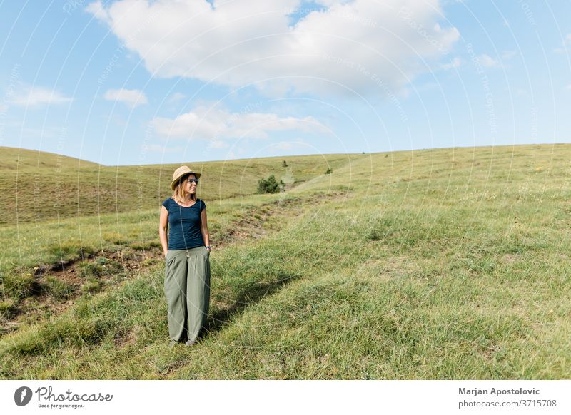 Young woman enjoying on the hillside meadows adult carefree casual caucasian cheerful countryside environment explore female field freedom grass green happiness