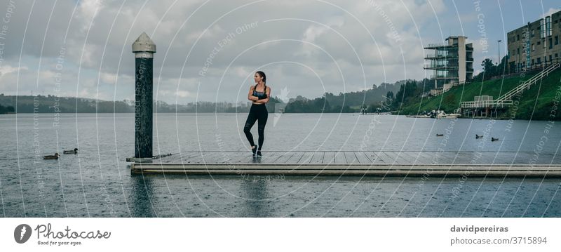 Sportswoman looking lake from pier rain sportswoman posing crossed arms serenity boxer braids fitness workout raining brave banner web panoramic panorama