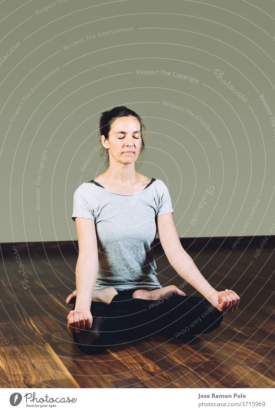 Woman sitting cross-legged on the floor doing yoga relaxation exercises. exercising people meditating women flexibility balance lifestyles lotus front view