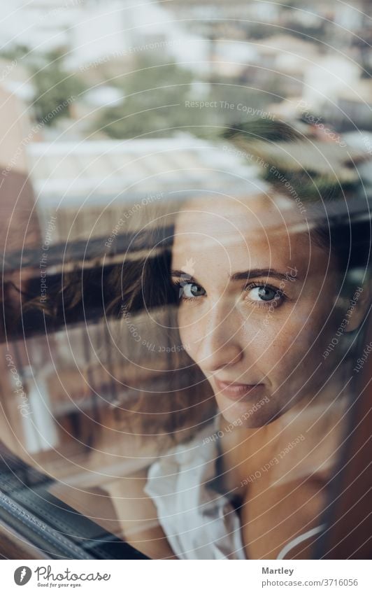 Portrait of a pretty brunette woman with blue eyes, looking at camera, photographed through glass. sexy lip portrait at home stay at home model bedroom glamour