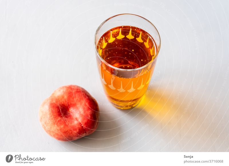 Iced tea in a glass with a fresh peach on a grey background Beverage Peach Glass Summer Refreshment Juice Sweet chill Fresh non-alcoholic fruit Delicious