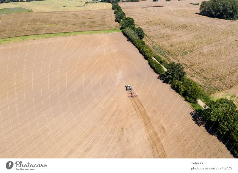 a tractor in a farming landscape with a plow from above tractor from above tractor with a plow field meadow dry nature earth dry earth crop mud eco farming