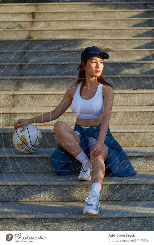 Slim sportswoman with basketball on stairs street city street style stone sportswear athlete female asian ethnic calm step relax training healthy wellness