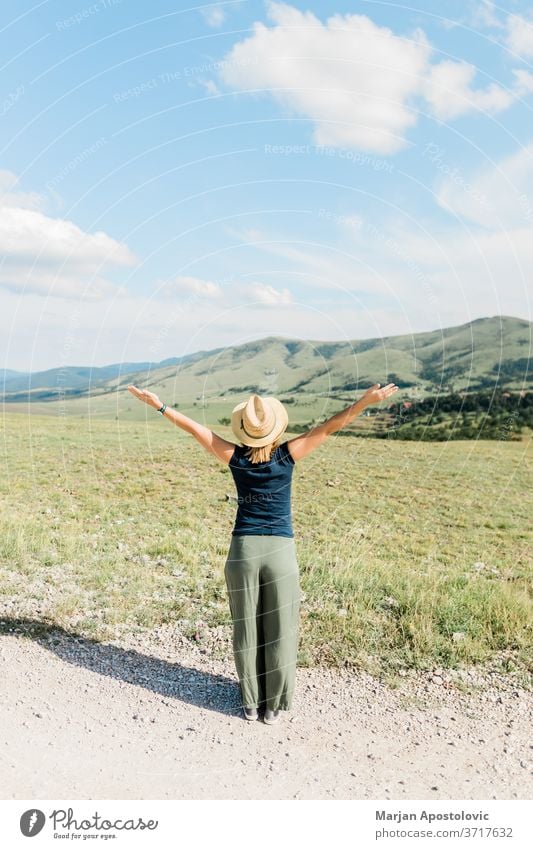 Young female nature lover enjoying the view of a mountain range in summertime adventure arms beautiful carefree casual europe explore freedom girl happiness