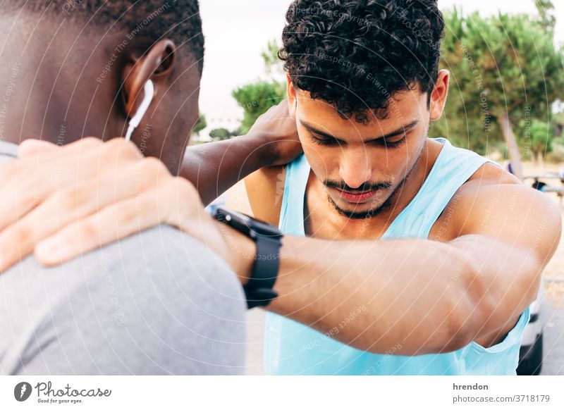 two young men warm up before starting to exercise stretching sport fitness exercising beginnings bonding runner standing together togetherness sunlight