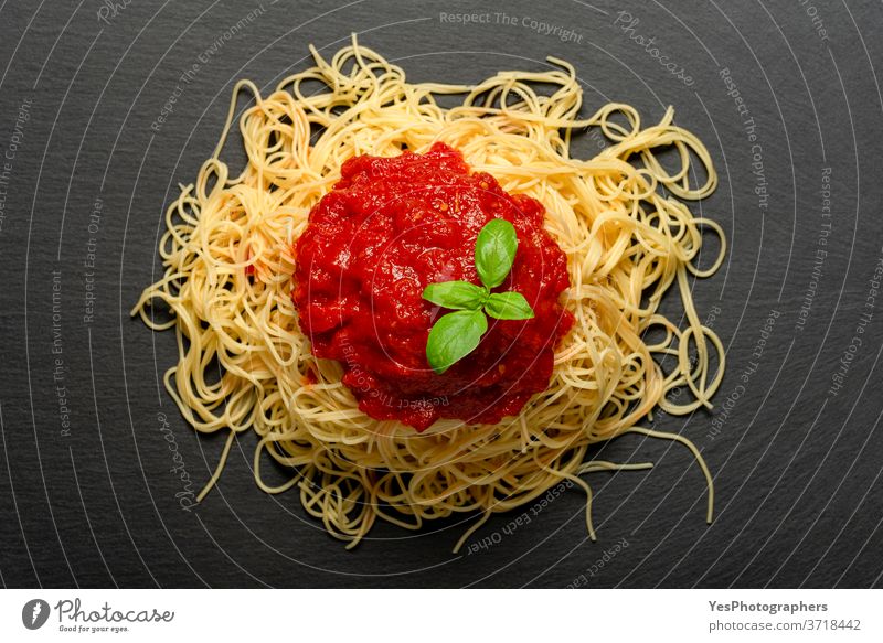 Spaghetti with tomato sauce on a black granite plate. Cooked spaghetti with red sauce. above view background baked basil carbohydrate carbs close-up