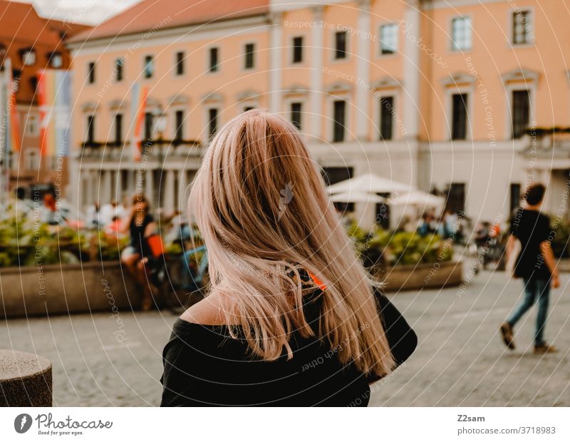 Young woman on the Bismarckplatz in Regensburg bismarckplatz Street life Town urban Summer Sun Lifestyle public space Blonde long hairs back view take a look