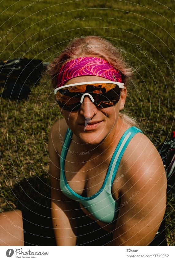 Sporty young woman takes a break Sportsperson sportswoman Young woman girl Top Sportswear sunglasses Headband Brown Skin Body athlete Summer Sun Meadow Blonde