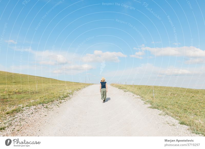 Young female nature explorer walking on a gravel road in summertime adult adventure alone beautiful caucasian challenge countryside dirt environment footpath