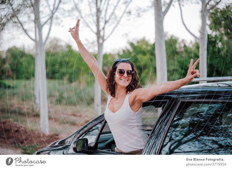 happy young woman in a car. travel and happiness concept outdoors way trip caucasian lifestyle enjoy people attractive automobile gorgeous casual attire smiling