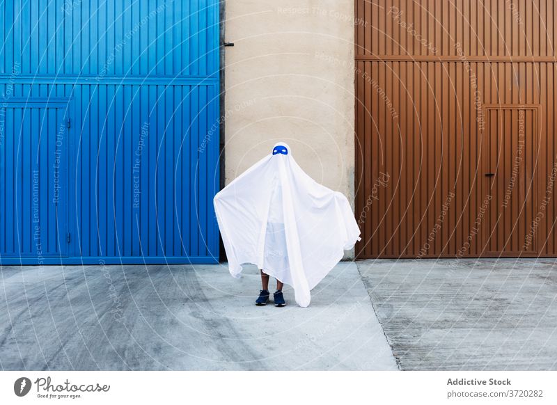 Anonymous kid in ghost costume in city halloween frighten child holiday entertain spooky autumn creepy scary event celebrate fall fantasy season street urban