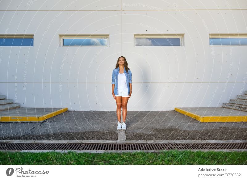 Woman in summer clothes standing with her eyes closed in a car park satisfaction lifestyles positivity recovery serenity relaxed millennial confidence mature