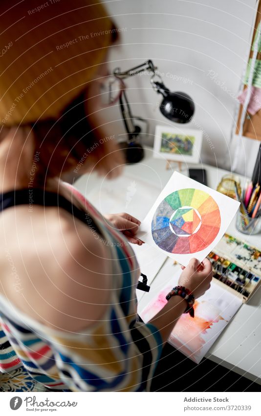 Creative woman at table in workshop artist painter color wheel project artwork create talent female skill occupation paper modern hobby studio contemporary