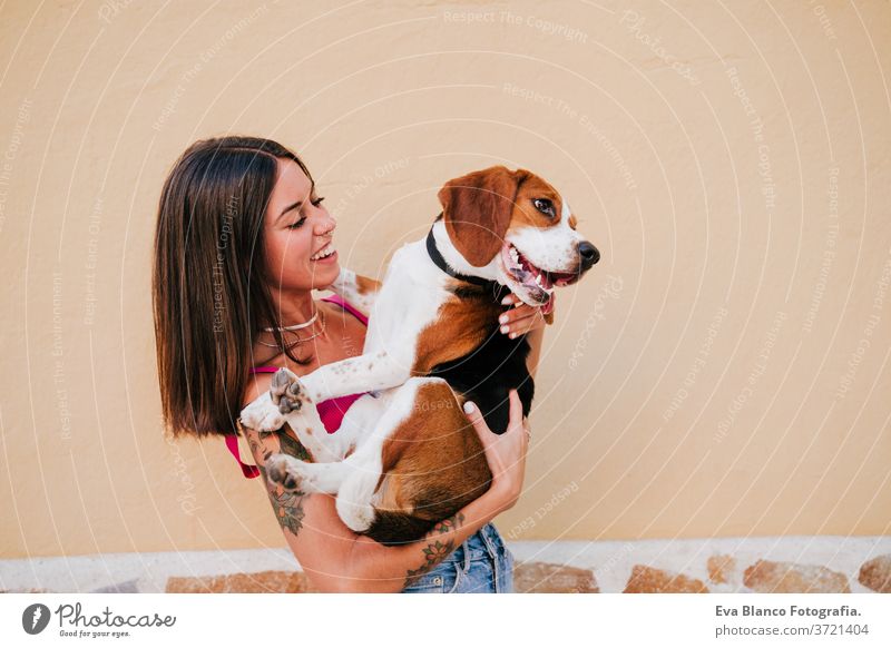 happy young woman outdoors having fun with beagle dog. Family and lifestyle concept. yellow background city love hug urban adult adventure affection beautiful