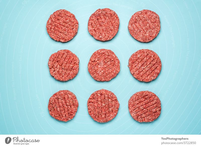 Raw hamburger patties isolated on blue background. Burger raw meat top view. above view aligned barbeque bbq beef butcher comfort food cooking cow meat cuisine