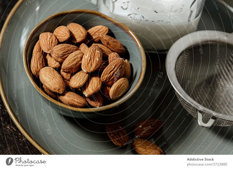 Bowl of almonds near bottle and sieve milk vegan natural bowl plate organic seed fresh ceramic strainer drink vegetarian super food vitamin portion kernel bunch