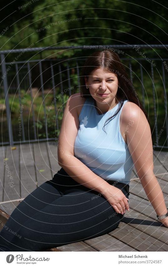 Young woman with open hair sitting on a wooden terrace in the sun Woman,sun, portrait Day Exterior shot Colour photo Contentment Serene natural Long-haired