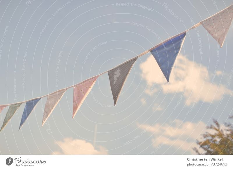 self-sewn pennant chain made of colourful fabrics in the sunlight against a slightly cloudy blue sky Self-made Cloth Cloth pattern Sun Sky Clouds Blue