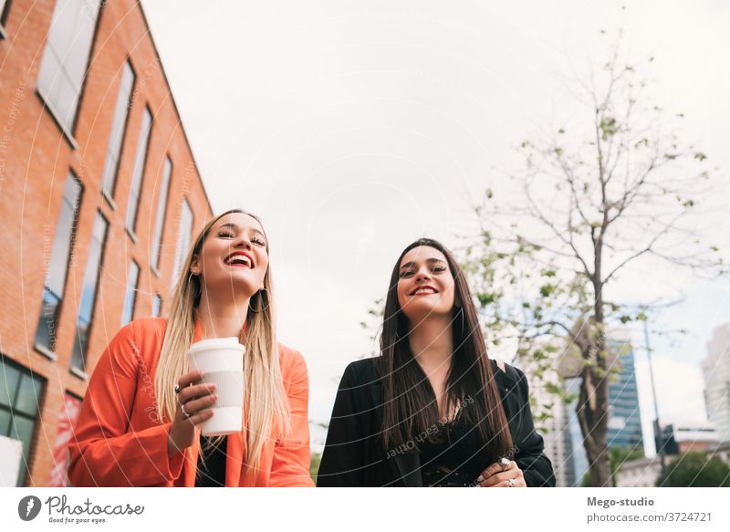 Two young friends walking together outdoors. two street city smiling pretty talking girlfriend town concept view style travel weekend looking enjoyment outside