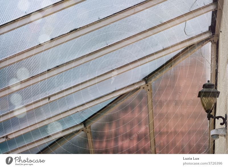 An old-fashioned glass roof and a yellow lamp, with shimmering raindrops Canopy Glass roof Lamp Entrance Gloomy Old nostalgically Morbid Roof Roofing tile Light