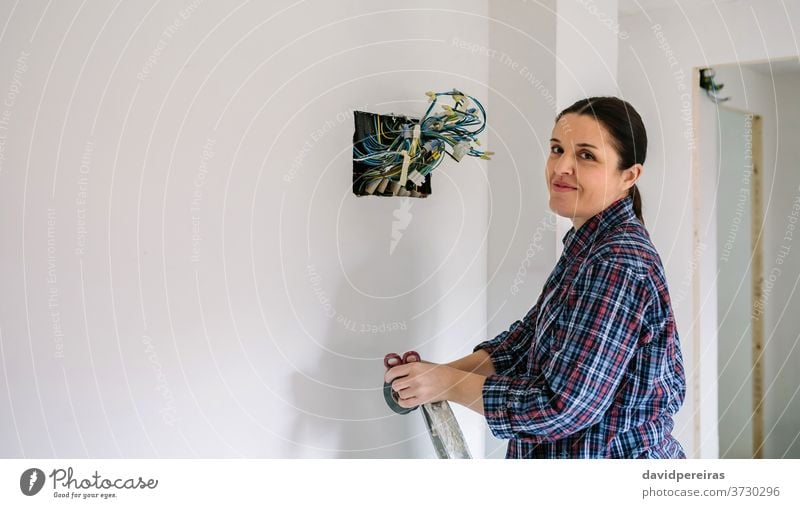 Electrician working on the electrical installation of a house electrical technician female electrician looking camera smiling connecting electric wire