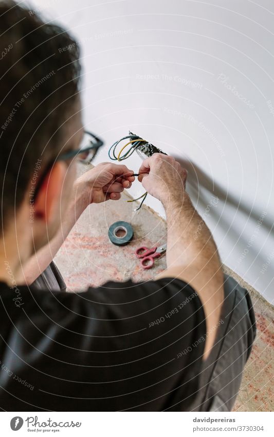 Electrician working on the electrical installation of a house electrician unrecognizable electrical technician wrapping electrical tape protecting