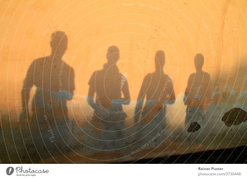 Shadow of four young men against a wall during sunset background dusk friends group group of friends outdoor people person shadow silhouette sunlight sunrise