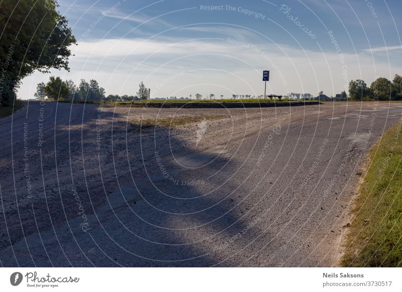 lonely country road crossroads with bus stop and blue sky Road sign Transport Street Sign Deserted Exterior shot asphalt Crossroads Triangle clouds shadow trees