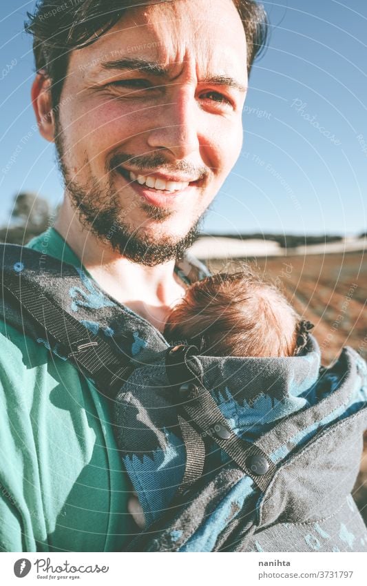 Single male parent carrying her baby with a backpack dad newborn front kangaroo single single parent family outdoors summer fall sunlight take a walk modern