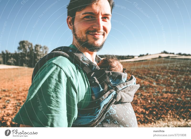 Single male parent carrying her baby with a backpack dad newborn front kangaroo single single parent family outdoors summer fall sunlight take a walk modern