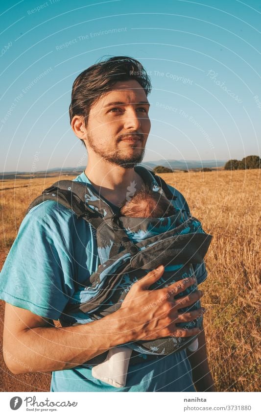 Single male parent carrying her baby with a backpack dad newborn front kangaroo single single parent family outdoors summer fall sunlight take a walk modern