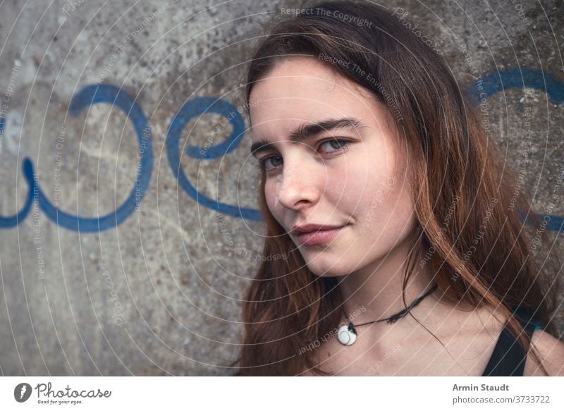 portrait of a smiling young woman with the word we on a wall teen teenager girl casual caucasian female outdoors lucky happy beautiful long hair confident