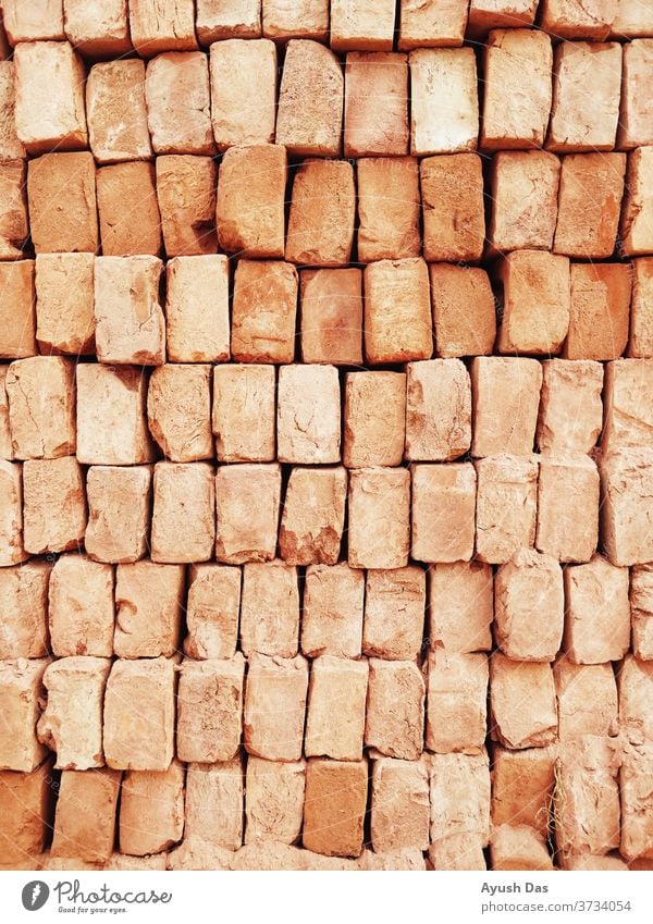 A stack of red bricks fills the frame in which the building is being constructed in India Dirty Old Cement Vintage Concrete Design background Masonry Surface