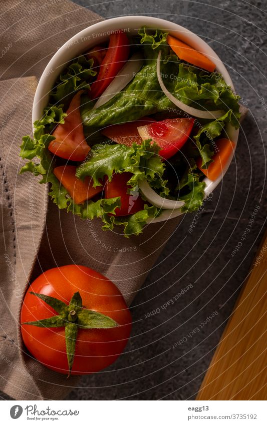 Tomatoes in salad inside a white bowl on grayish background tomato food grocery still-life vegetables lettuce organic mediterranean backgrounds composition