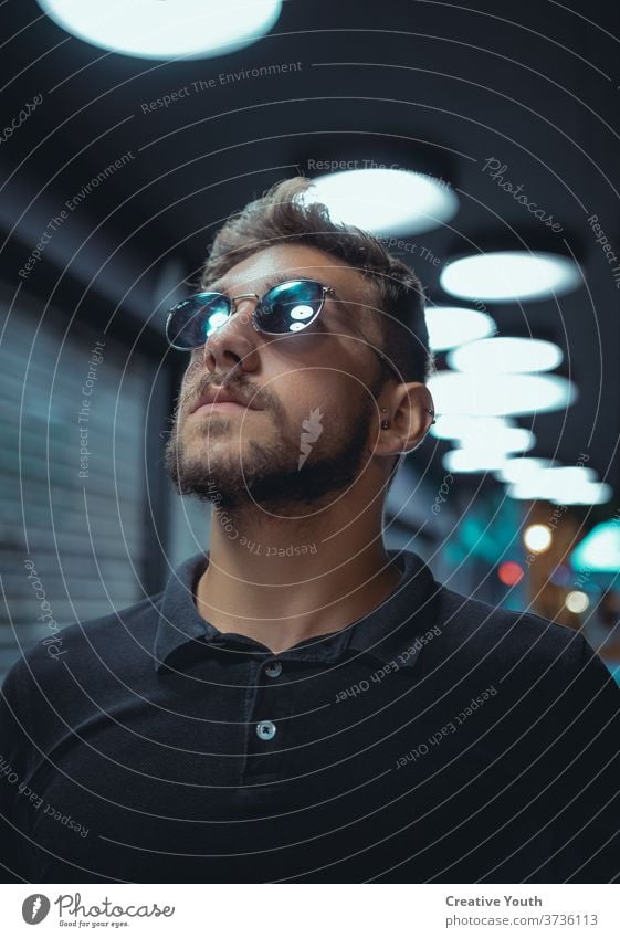 Portrait of a man with low angle Man Beard Glass Eyeglasses Light Glare Yellow warm blue-green and orange dirty hair T-shirt Polo shirt Reflection portrait