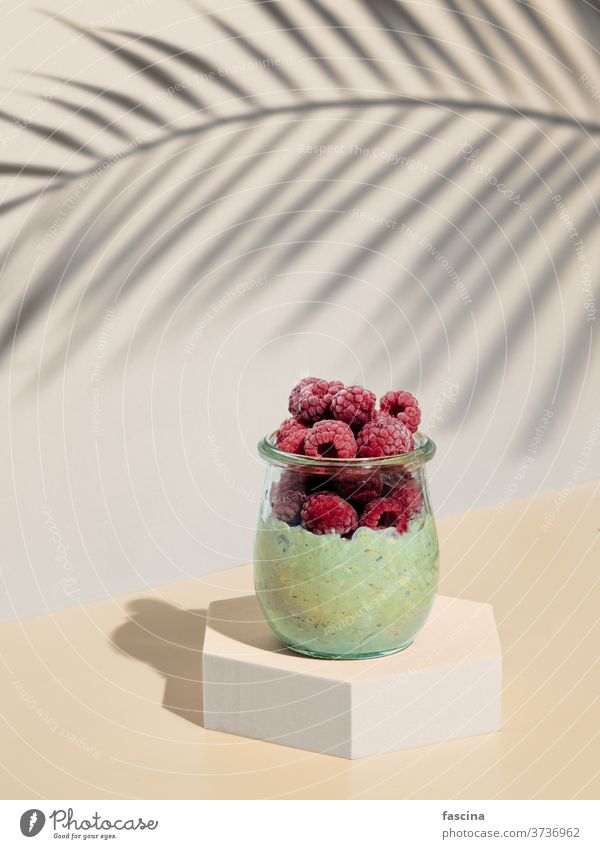 Green matcha overnight oats wits raspberries raspberry still life breakfast green food minimalistic pedestal composition trendy copyspace conceptual tall