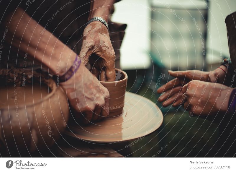 close up of hands of a potter and his student learning pottery clay wheel craft art ceramic work ceramics handicraft skill bowl making artist handmade finger