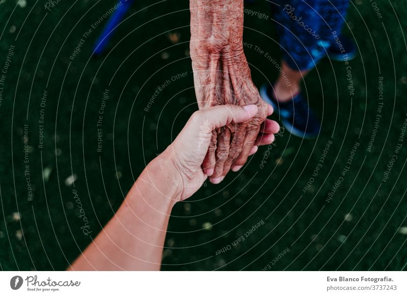 close up of of lady holding hands with young unrecognizable woman. Two generations old lady young woman grandmother granddaughter love together family touching