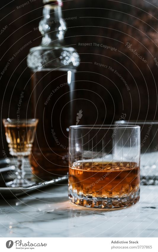 Glass of alcohol beverage on marble table whiskey bar glass drink bottle serve counter booze refreshment pub transparent modern style cold event celebrate