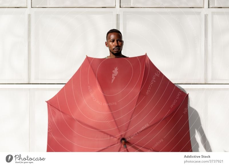 African American man with umbrella in street cover hide summer sunny city urban pavement male ethnic black african american sidewalk body town trendy weather