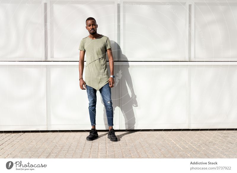 Serious black man on city street urban building serene enjoy sunlight modern pavement male ethnic african american sunny weather relax style calm trendy