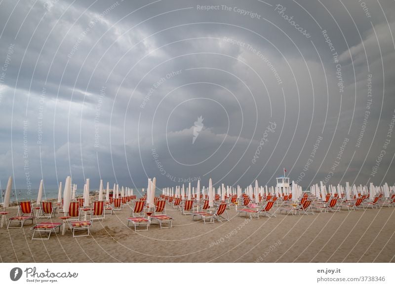 s'isch over - summer holiday - beach with deck chairs and closed parasols, because a thunderstorm with dark clouds is coming up to the horizon Beach Storm