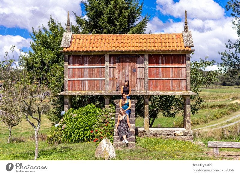 Three friends sitting on an horreo in Galicia, Spain three tourists galicia spain construction rural storage food typical cross spaniard spanish tile north wood