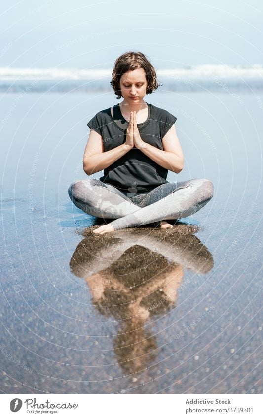 Slim woman doing meditation on beach yoga sea practice asana pose twist eyes closed sit balance calm seashore harmony wellness lifestyle flexible female nature