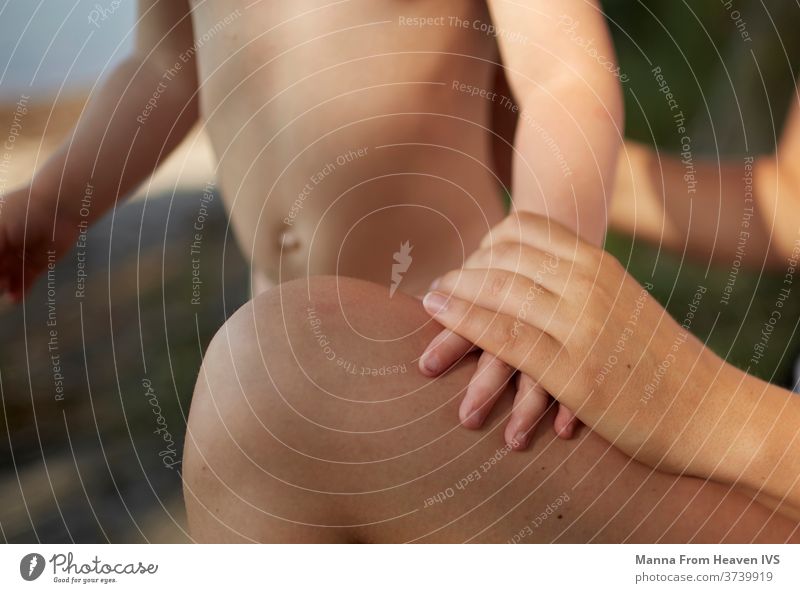 Mother holding her son's hand at the beach after a swim mother skin forest love child childhood loving kid kids care caring hands people family young parent