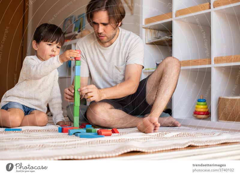 kid and his father playing at home with wood building blocks. Homeschooling. Stay at home. Family time covid-19 safe coronavirus stay at home quarantine family