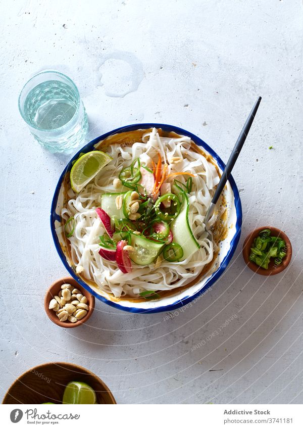 Vegan rice noodles salad food vegan top view cucumber vegetable lime peanut sauce asian cookery chinese fresh dinner green healthy bowl eating chopstick